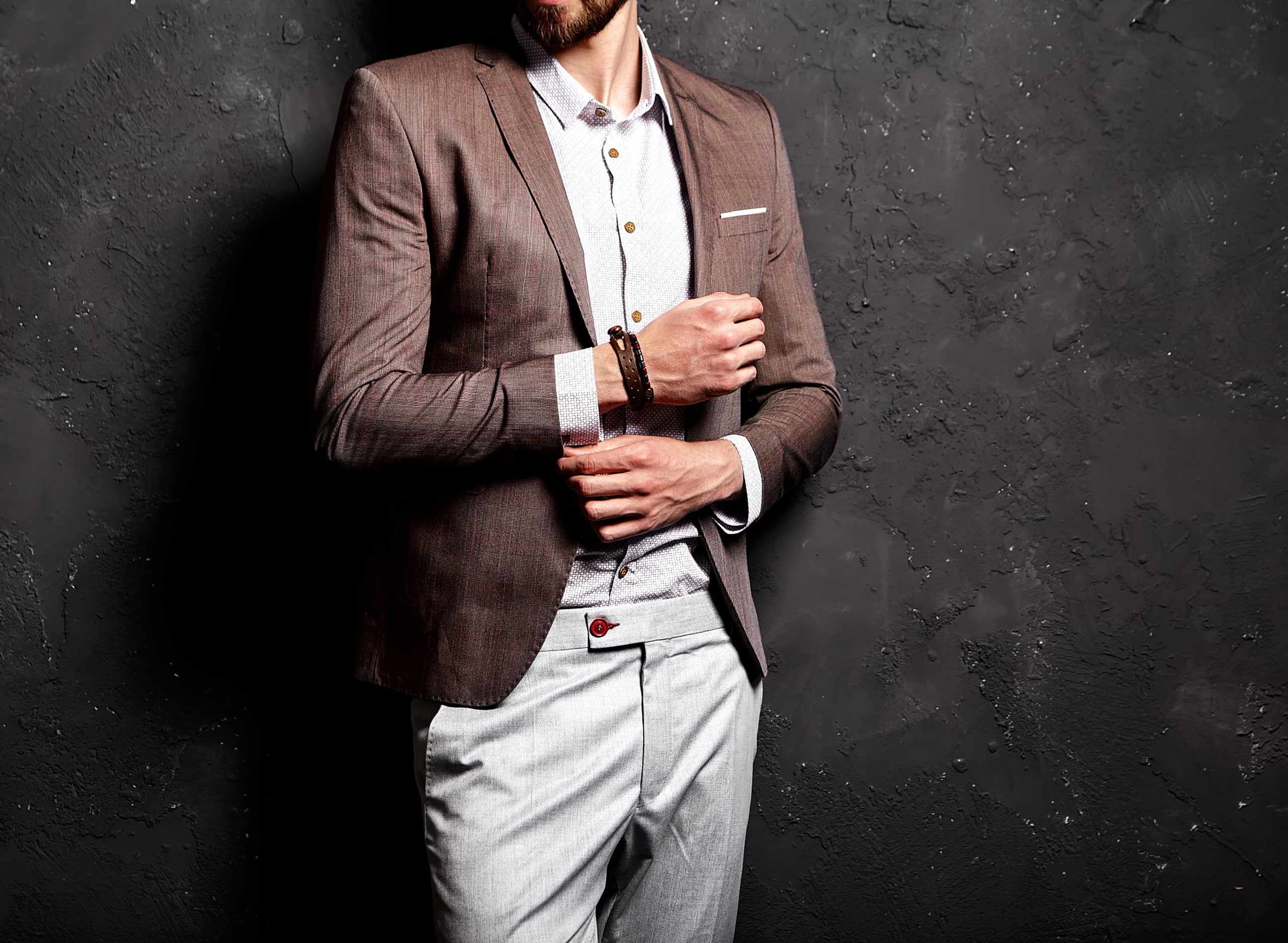 portrait-handsome-fashion-stylish-hipster-businessman-model-dressed-elegant-brown-suit-near-dark-wall-min